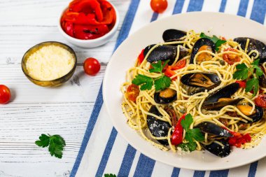 Tahta arka planda midye ve domatesli deniz ürünleri makarna spagettisi. İtalyan mutfağı. Seçici odak.