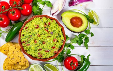 Bir kase Guacamole yanında Taze Malzemeler Tortilla cipsli bir masada. Seçici odak.