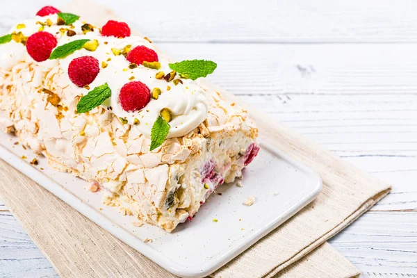Meringue Roll Cake Pavlova with Cream and Raspberries. Meringue Roulade, Summer Dessert. Selective focus.