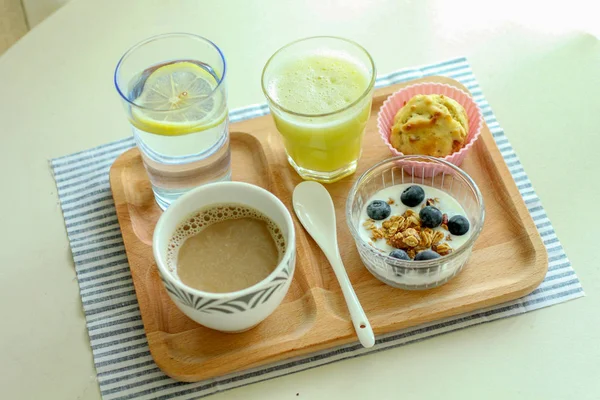 Café da manhã saudável com iogurte de mirtilo, biscoito, suco, água e café — Fotografia de Stock