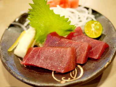 ton balıklı sashimi - daikon (beyaz turp) üzerinde maguro (taze çiğ balığı). zencefil, wasabi, deniz yosunu, salatalık, salata yaprağı ve limon ile süslenmiş