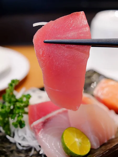Fresh tuna sashimi held by a pair of chopsticks — Stock Photo, Image