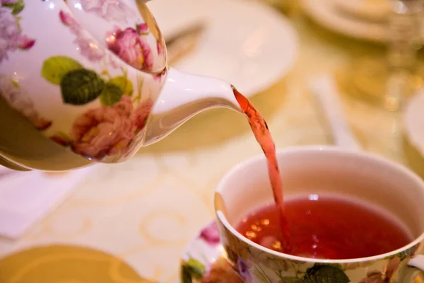 Close-up de derramar chá inglês com belo conjunto de chá — Fotografia de Stock