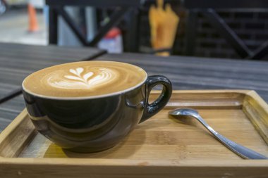 Sıcak sanat Latte kahve bir fincan ahşap tepsi ve kahve dükkanı bokeh görüntü ile arka plan bulanıklık.