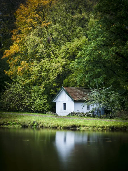Une petite maison au bord d'un lac avec réflexion Photo De Stock
