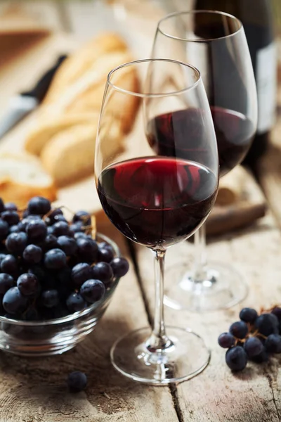 Red wine, bread and grapes on wooden background