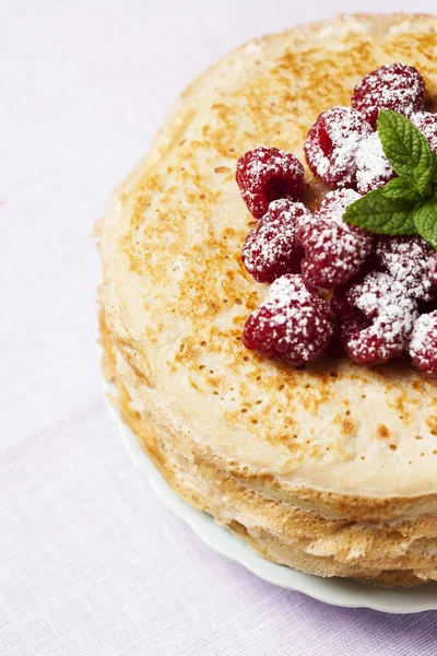 Stack of Russian-style pancakes with raspberries