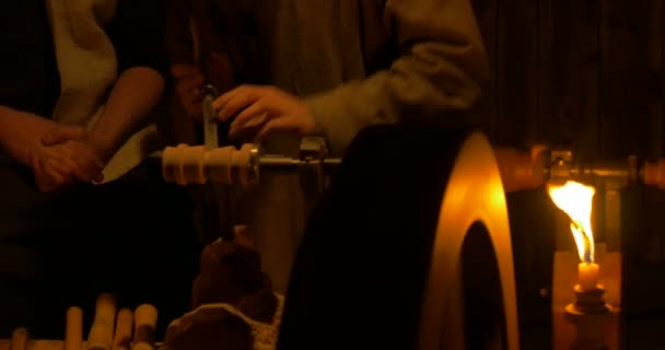 Um velho torno de madeira com fuso girando iluminado pela luz de velas — Vídeo de Stock