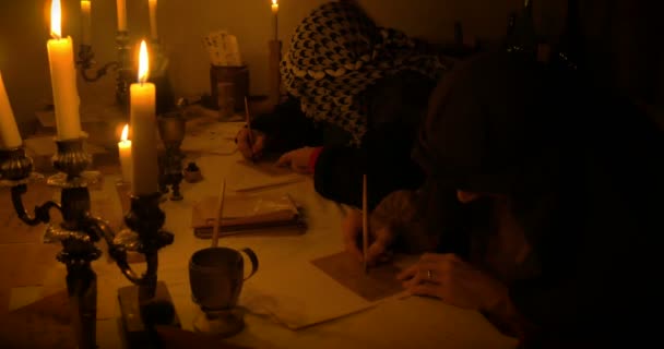 Antiguos escribas escribiendo una carta iluminada por velas — Vídeo de stock