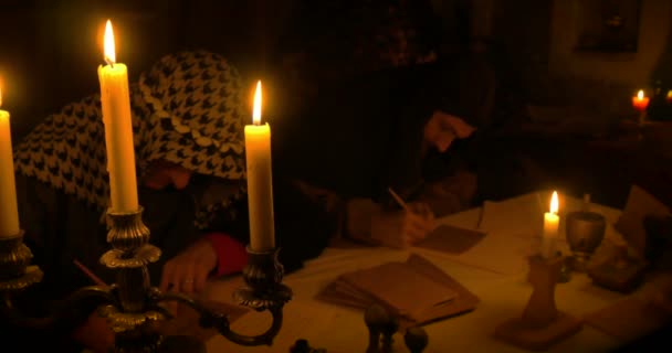 Antiguos escribas escribiendo una carta iluminada por velas — Vídeos de Stock
