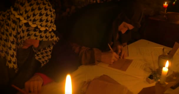 Ancient scribes writing a letter illuminated by candlelight — Stock Video