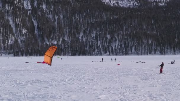 Snowkiter snaží zvednout jeho draka na zamrzlém jezeře 