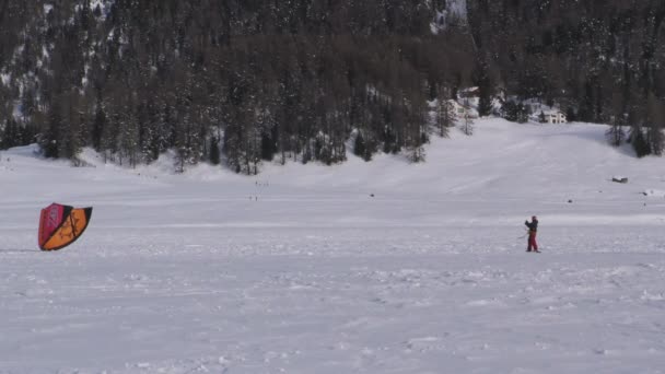 En snowkiter som försöker lyfta sin kite på en frusen sjö — Stockvideo