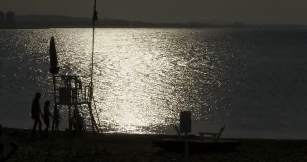 Silueta de una familia en la orilla del mar al atardecer — Vídeos de Stock