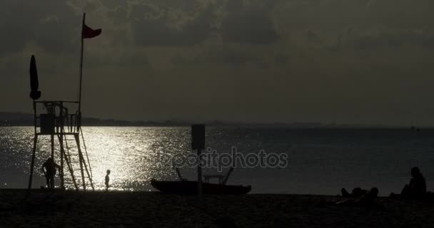 Silhouette eines Kindes, das am Strand mit Sand spielt — Stockvideo