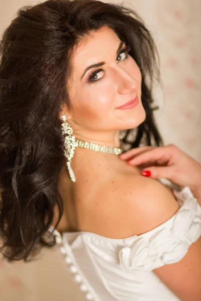 Studio portrait of a beautiful young woman. Brunette girl with hairstyle, wearing like bride. She in white corset with accessories. Soft focus — Stock Photo, Image