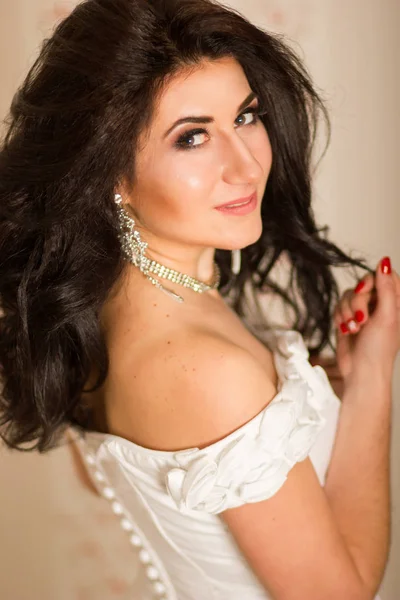 Studio portrait of a beautiful young woman. Brunette girl with hairstyle, wearing like bride. She in white corset with accessories. Soft focus — Stock Photo, Image