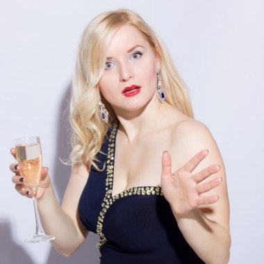 Güzel bir sarışın genç kadın mavi uzun gece elbisesi içinde stüdyo portre. Bir kız bir kadeh şampanya elinde tutuyor