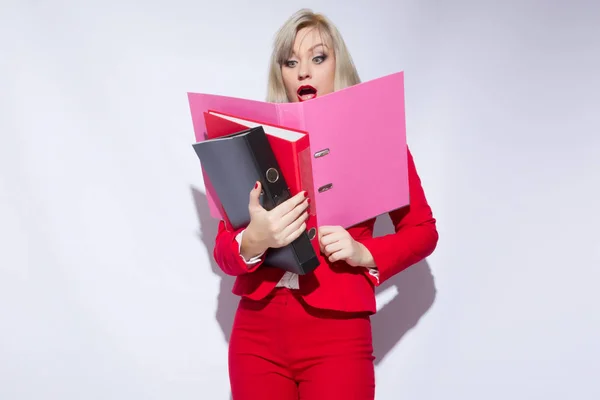 Portrait of a beautiful secretary in a red suit with folders in hand