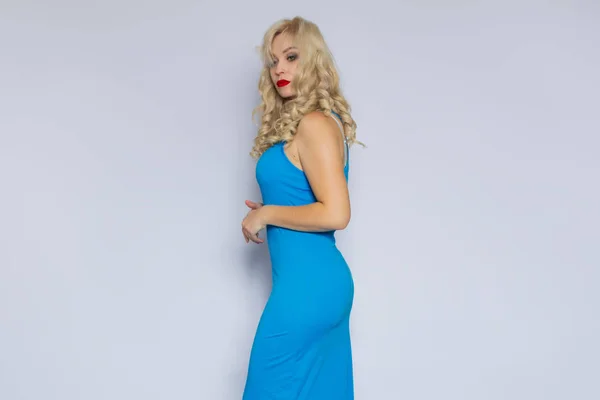 Gri Bir Arka Plan Üzerinde Uzun Mavi Elbiseli Kıvırcık Saçlı — Stok fotoğraf