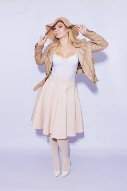 Tam uzunlukta portre güzel genç sarışın bir kadın. Kız MIDI bej etek ve kahverengi kısa ceket giymiş. Kafasına kahverengi şapka var. Bacaklar dantel çorap ve beyaz ayakkabı topuğu ile