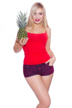 Sarışın ileri hafif bir gülümseme ile seksi görünüyor. O bir ananas onun yanında bir elinde tutar. İkinci el şort cebine itilir