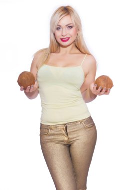 Güzel bir sarışın genç kadın bir yaz ışık sarı mayoyu ve altın kot stüdyo portre. Kız 2 Hindistan cevizi tutuyor. Kavram - bir kızla tropikal meyve. İzole