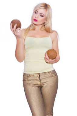 Güzel bir sarışın genç kadın bir yaz ışık sarı mayoyu ve altın kot stüdyo portre. Kız 2 Hindistan cevizi tutuyor. Kavram - bir kızla tropikal meyve. İzole