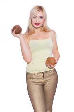 Güzel bir sarışın genç kadın bir yaz ışık sarı mayoyu ve altın kot stüdyo portre. Kız 2 Hindistan cevizi tutuyor. Kavram - bir kızla tropikal meyve. İzole