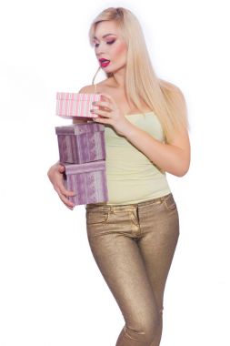 Studio fotoğraf güzel bir genç sarışın kadının uzun saçlı bir yaz ışık sarı mayoyu ve altın kot pantolon giymiş. Kız hediye kutuları tutuyor. Bir model beyaz bir arka plan karşı teşkil etmektedir.. 