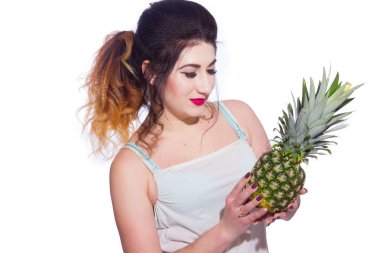 Yaz stüdyo uzun saçlı güzel bir genç esmer kadın portresi. Bir kız bir yaz tişört ve kot pantolon bir ananas onun elinde tutuyor. Konsept: yaz fotoğraf ve güneşli bir ruh hali