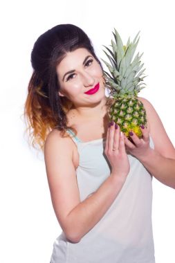 Yaz stüdyo uzun saçlı güzel bir genç esmer kadın portresi. Bir kız bir yaz tişört ve kot pantolon bir ananas onun elinde tutuyor. Konsept: yaz fotoğraf ve güneşli bir ruh hali