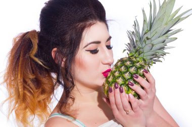 Yaz stüdyo uzun saçlı güzel bir genç esmer kadın portresi. Bir kız bir yaz tişört ve kot pantolon bir ananas onun elinde tutuyor. Konsept: yaz fotoğraf ve güneşli bir ruh hali