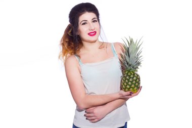 Yaz stüdyo uzun saçlı güzel bir genç esmer kadın portresi. Bir kız bir yaz tişört ve kot pantolon bir ananas onun elinde tutuyor. Konsept: yaz fotoğraf ve güneşli bir ruh hali