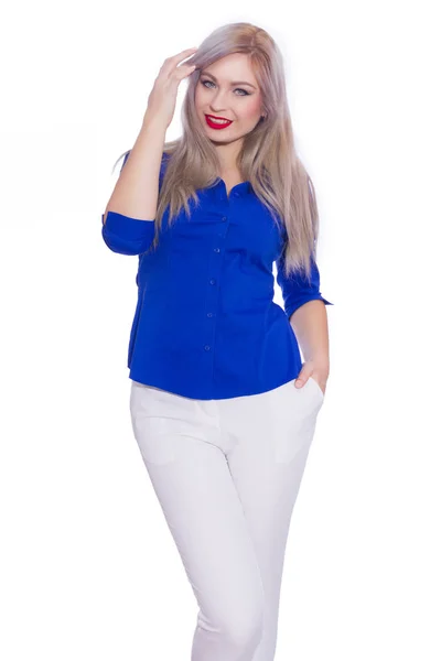 工作室的商业肖像一个年轻的金发女郎在深蓝色衬衫和白色长裤 在孤立的白色背景下假扮的女孩 微笑着看着摄像机 — 图库照片