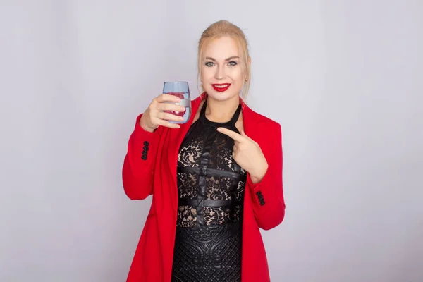 Blondynka trzymająca szklankę wody na jasnym tle — Zdjęcie stockowe