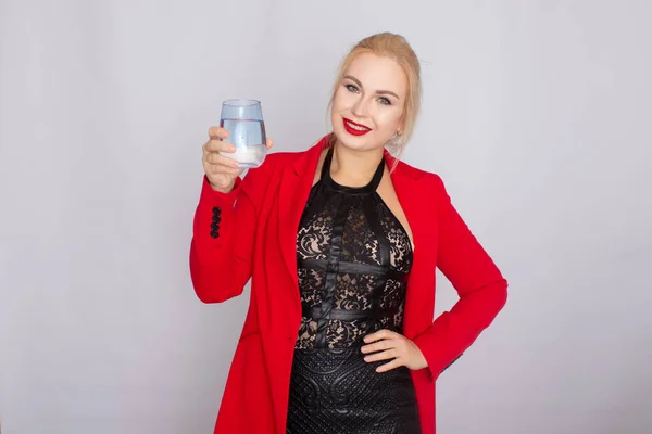 Blondine hält Wasserglas über hellem Hintergrund — Stockfoto