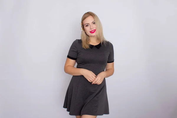 Attraktive blonde Schönheit im grauen Kleid posiert auf weißem Hintergrund — Stockfoto