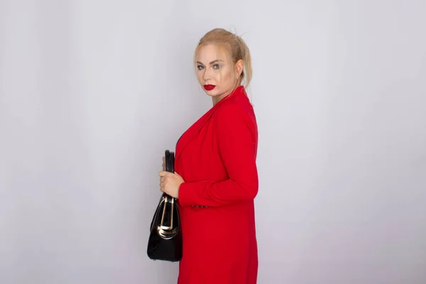 Geschäftsfrau in roter Jacke mit Tasche in der Hand — Stockfoto