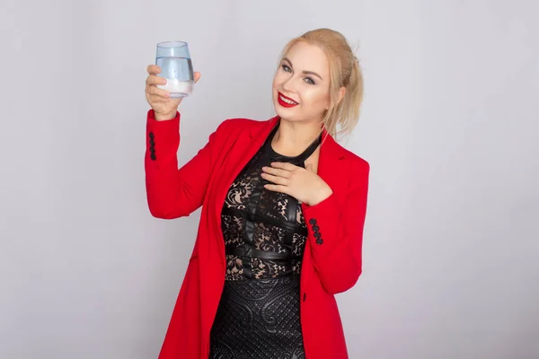 Blonde woman holding water glass over light background — Stock Photo, Image