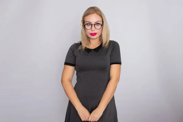 Young blond woman in grey short dress wearing glasses — Stock Photo, Image