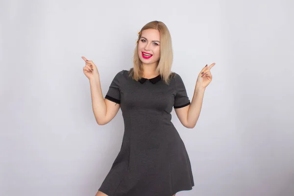 Attraktive blonde Schönheit im grauen Kleid posiert auf weißem Hintergrund — Stockfoto