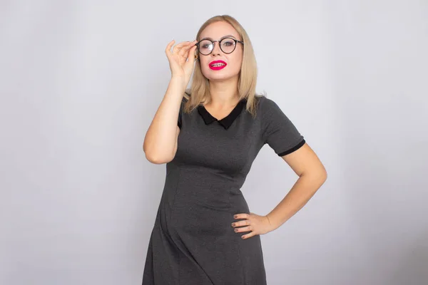 Молода блондинка в сірій короткій сукні в окулярах — стокове фото