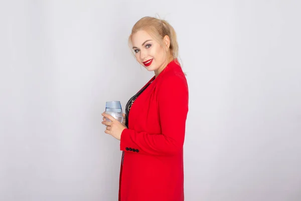 Blonde woman holding water glass over light background — ストック写真
