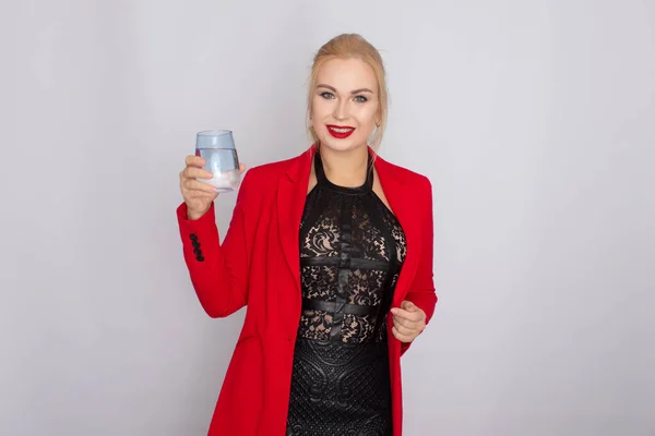 Blondine hält Wasserglas über hellem Hintergrund — Stockfoto