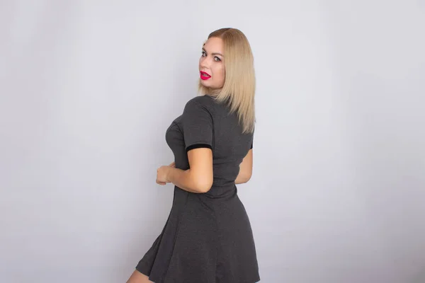 Attractive blonde beauty in grey dress posing on white background — Stock Photo, Image