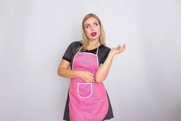 Blondýny žena v šedých šatech na sobě kuchyně bílá a růžová zástěra — Stock fotografie