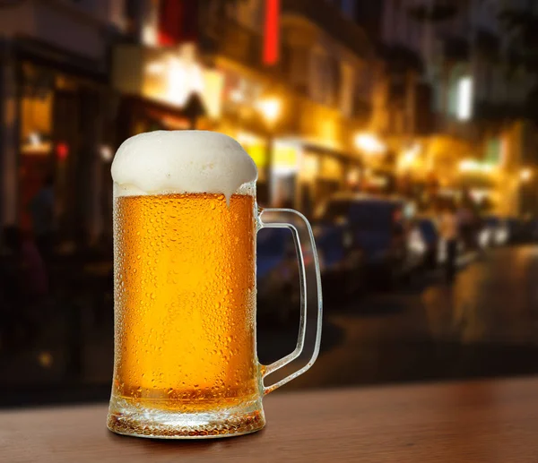 Mug with beer on the background of a outside bar.