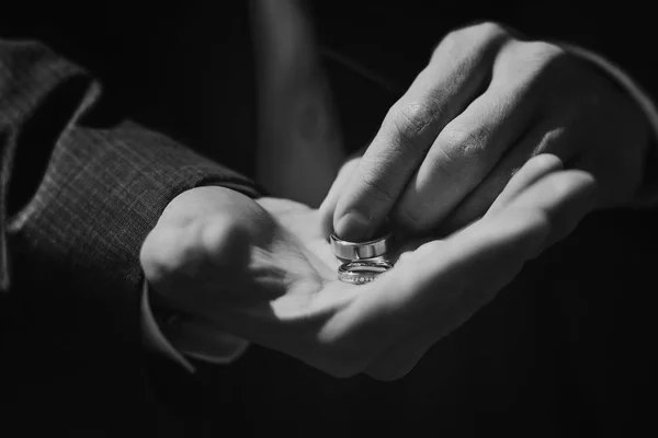 Groom holding wedding rings, waits for his bride