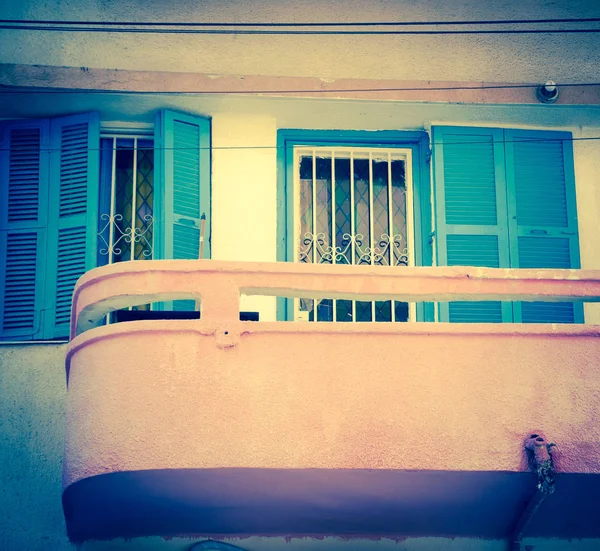 Pembe balkon ve pencere eşiği ile renkli vitray ve turkuaz kepenkleri. Eski bina ile sıva duvar. Bauhaus mimari tarzı. Tel Aviv, İsrail. Yaşlı fotoğraf. 